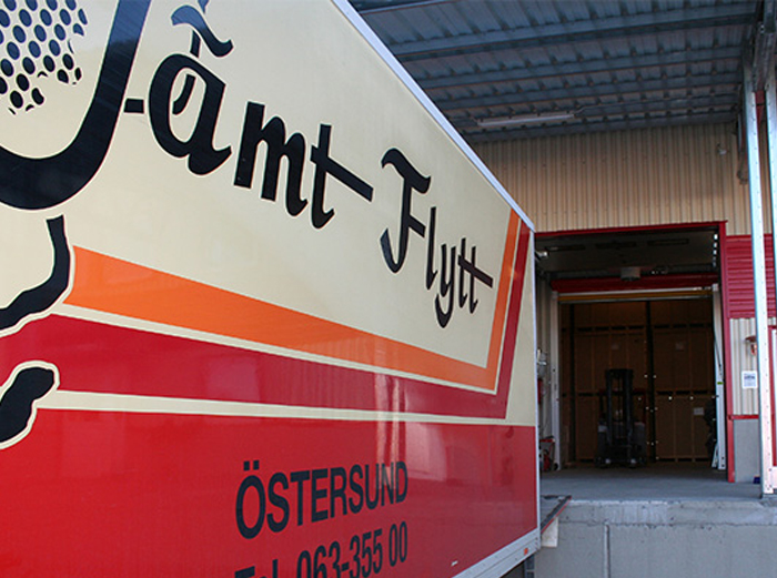 magasinering_3 Jämt Flytt-lastbil vid magasin med öppen släpdörr och gaffeltruck synlig.